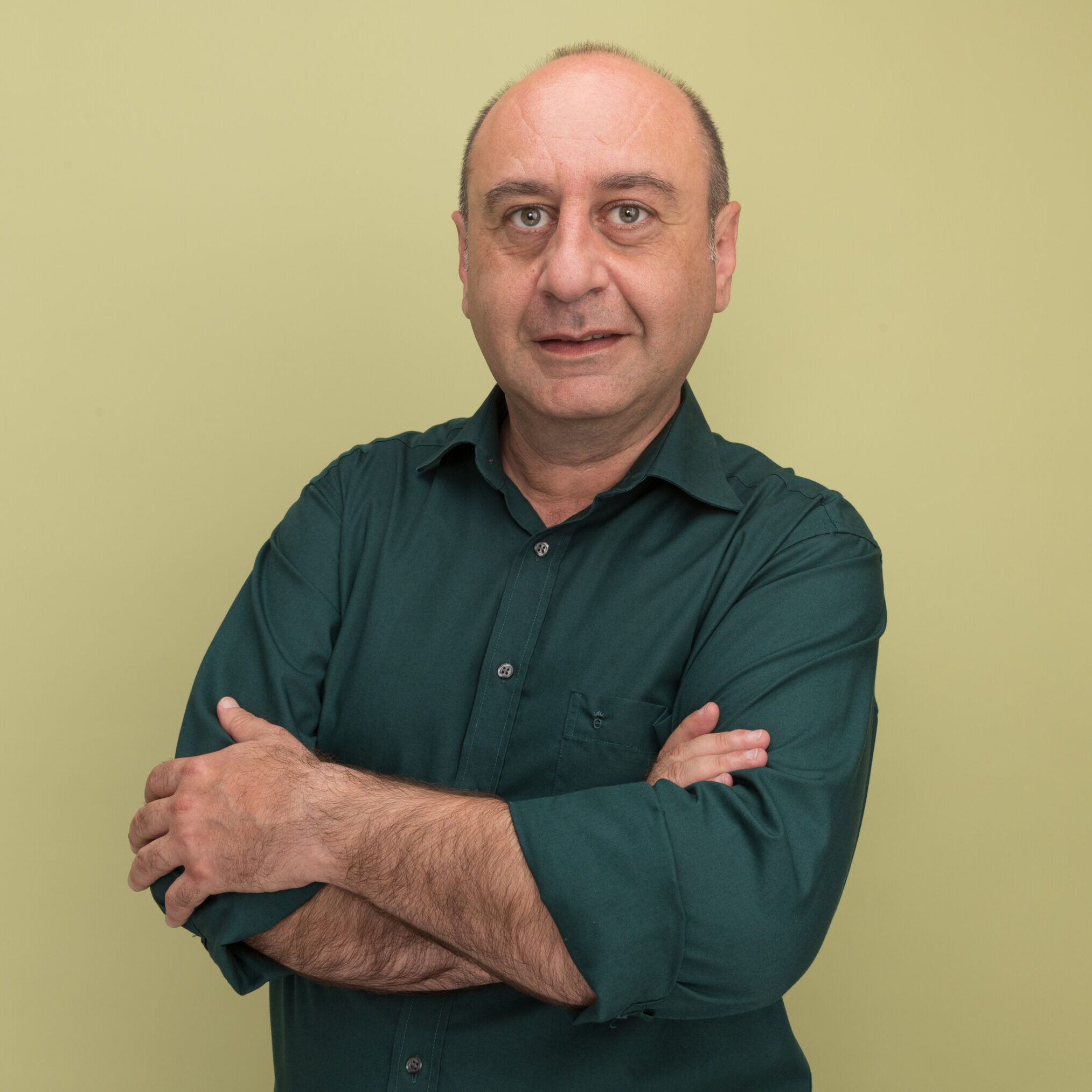 pleased middle-aged man wearing green t-shirt crossing hands isolated on olive green background